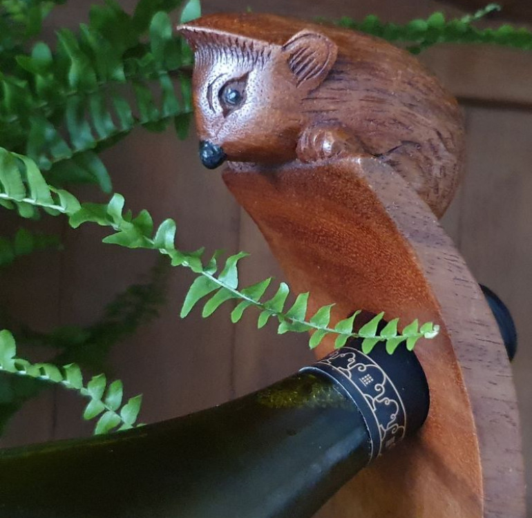 hand carved curved wine bottle stand with a hedgehog design