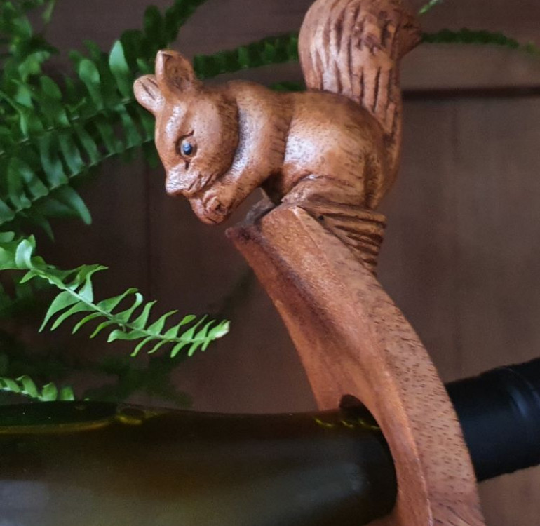 hand carved curved wooden balancing wine bottle holder with a squirrel peering over the top design