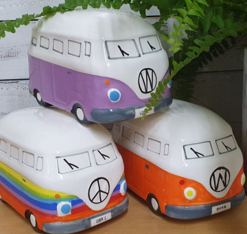 A selection of small brightly coloured ceramic VW Campervan money boxes