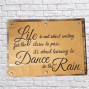 a wooden backboard with a painted and embossed front reading life is not for waiting for the storm to pass. It's about learning to dance in the rain