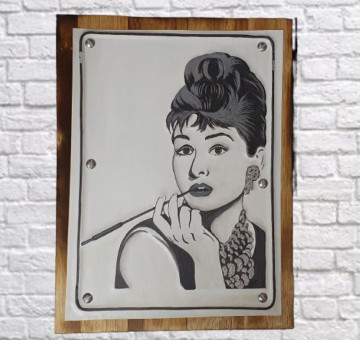 A wooden backboard with a painted and tin embossed front picture of the iconic Audrey Hepburn