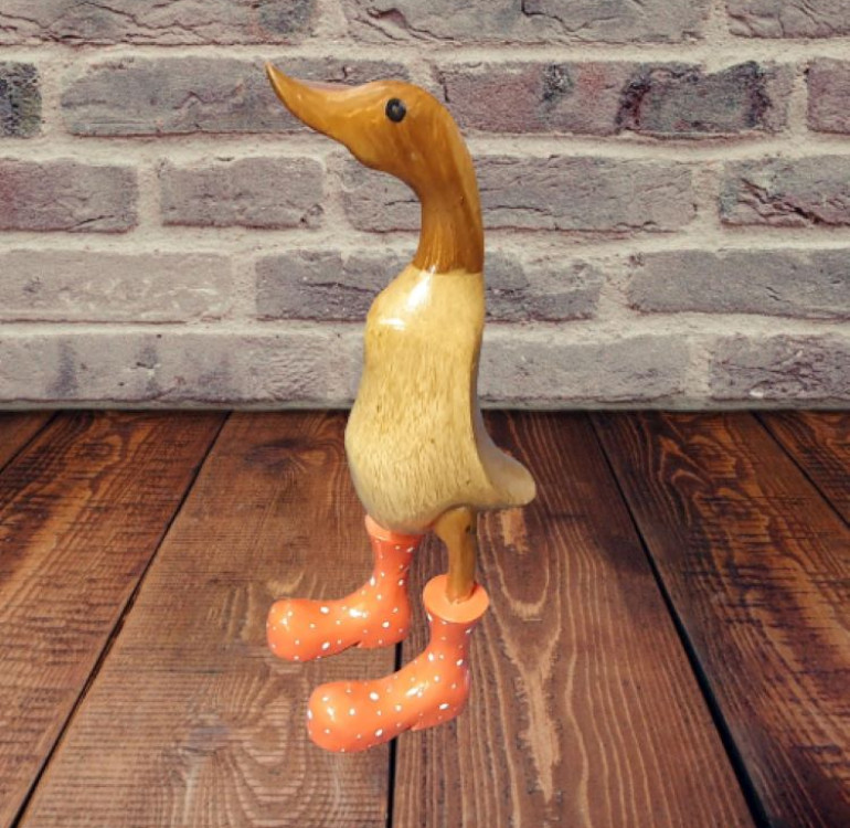 a small hand carved bamboo duck with orange boots, they have white spots on