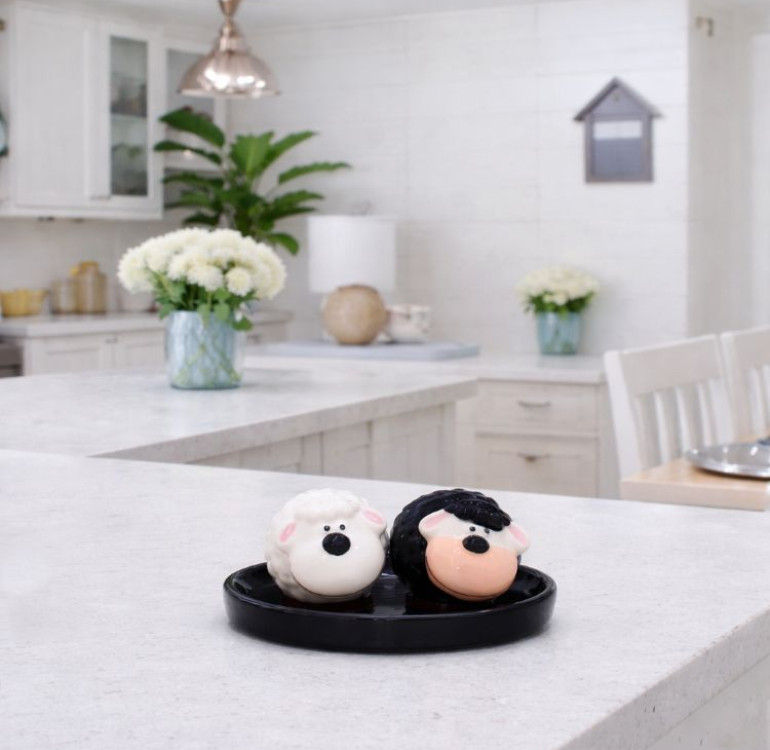 a set of ceramic black and white sheep salt and pepper shakers on a ceramic base