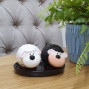 a set of ceramic black and white sheep salt and pepper shakers on a ceramic base