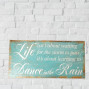 a wooden painted sign with the words Life isn't about waiting for the storm to pass it's about learning to Dance in the rain, coastal wind washed sign with twisted rope hanging