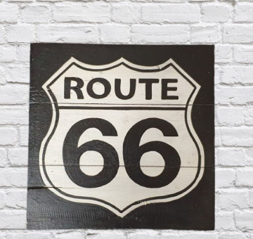 a black and white painted wooden sign "Route 66" logo