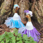an image of 2 bamboo ducks in blue and purple dresses with hats and corresponding bow ribbons on