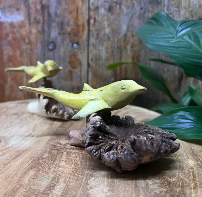 an image of a carved dophin swimming attached to a natural piece of parasite woodOur beautiful hand carved dolphin attached to parasite wood is a stunning ornament for any home. This is a Fairtrade item made by our skilled team using the Parasite wood that attaches itself to already growing trees, as the parasite grows it distorts to make gorgeous, intricate and unique designs.