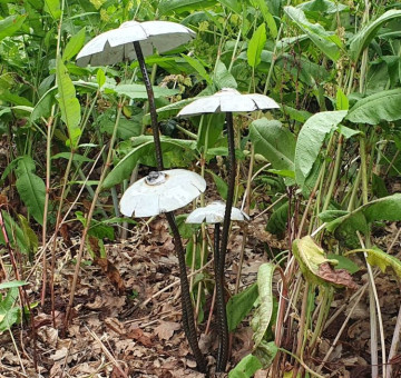 a garden sculpture of a set of white recycled metal mushrooms