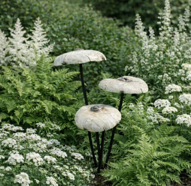 a garden sculpture of a set of white recycled metal mushrooms