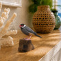 a hand carved and hand painted Java Sparrow standing on a piece of wood