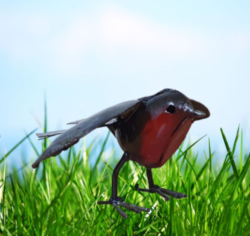 a handmade recycled metal little robin for outdoors with its wings open ready to fly