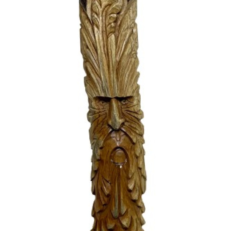 a hand carved wooden green man measuring 1m on a half log