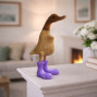 a small bamboo duck, hand carved with bright pink boots on