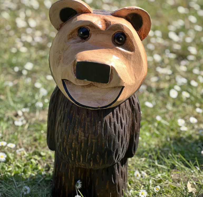 a hand carved outdoor wooden bear sculpture, smiling happy bear