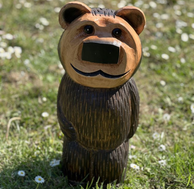 a hand carved outdoor wooden bear sculpture, smiling happy bear