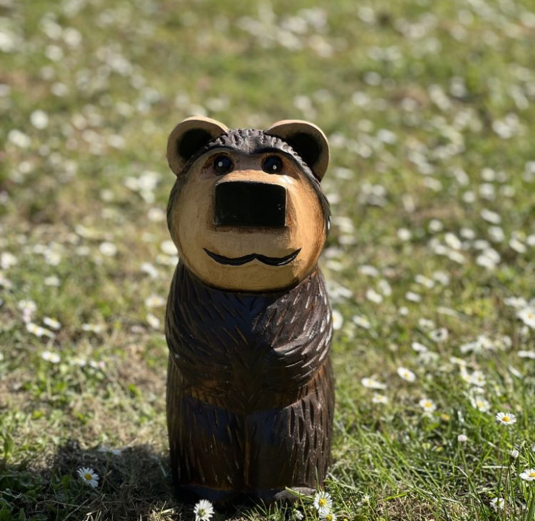 a hand carved outdoor wooden bear sculpture, tired squinty eyes
