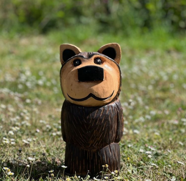 a hand carved outdoor wooden bear sculpture, tired squinty eyes