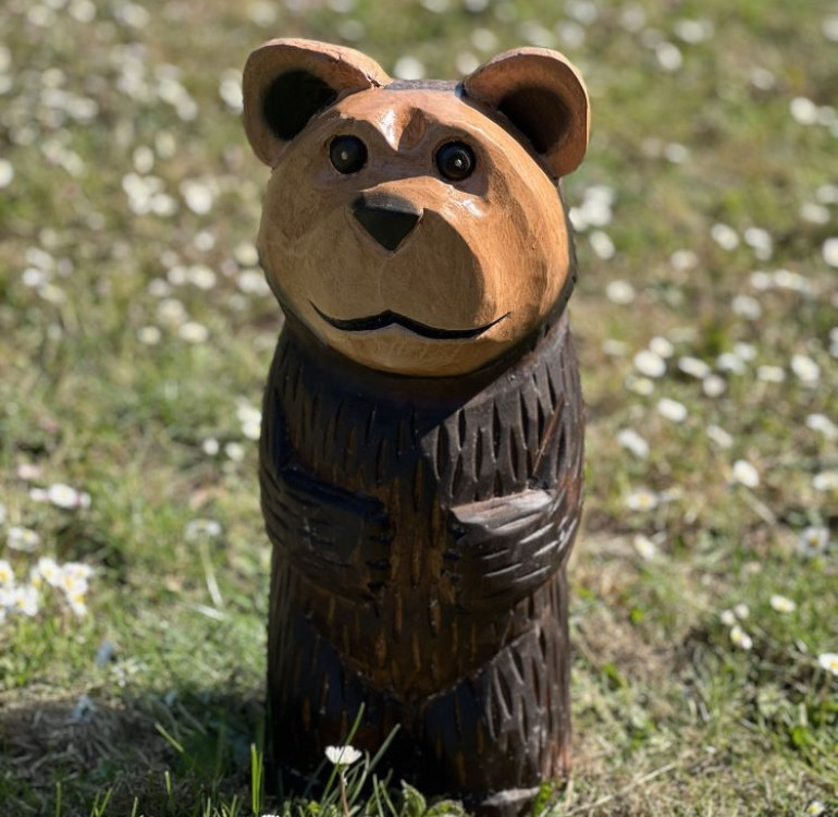a hand carved outdoor wooden bear sculpture, smiling happy bear