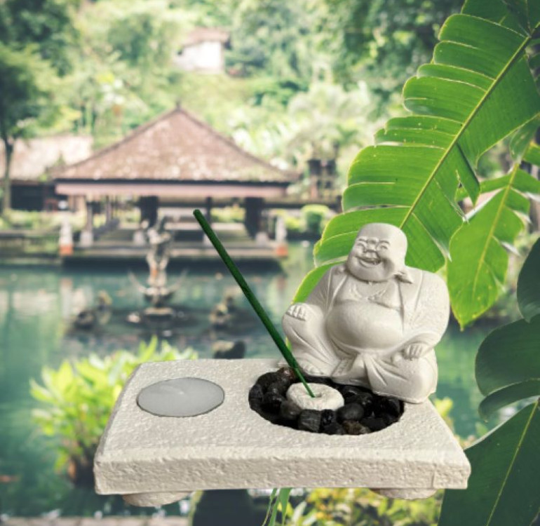 a white stone effect buddha on garden with incense sticks and candle