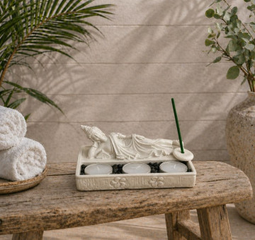 a white stone effect buddha on garden with incense sticks and candle
