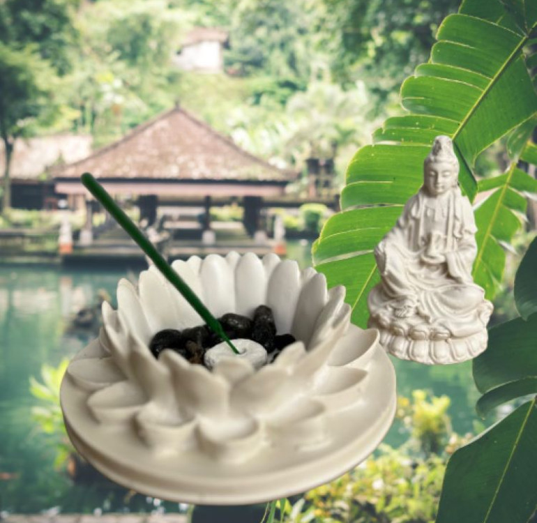 a white stone effect buddha on garden with incense sticks