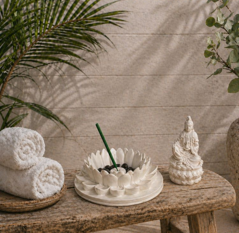 a white stone effect buddha on garden with incense sticks