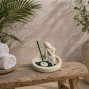 a white stone effect buddha on garden with incense sticks and candle