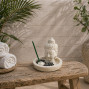 a white stone effect buddha on garden with incense sticks and candle