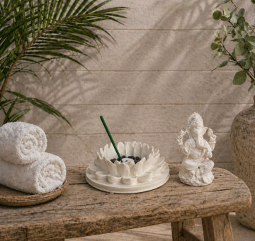 a white stone effect buddha on garden with incense sticks and candle