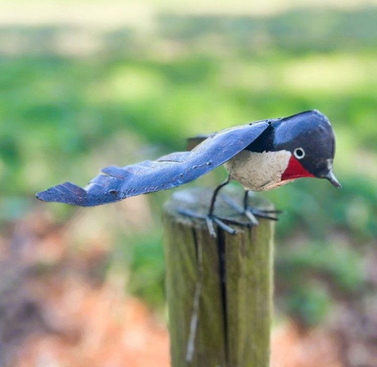 a handmade recycled metal little robin for outdoors with its wings open ready to fly
