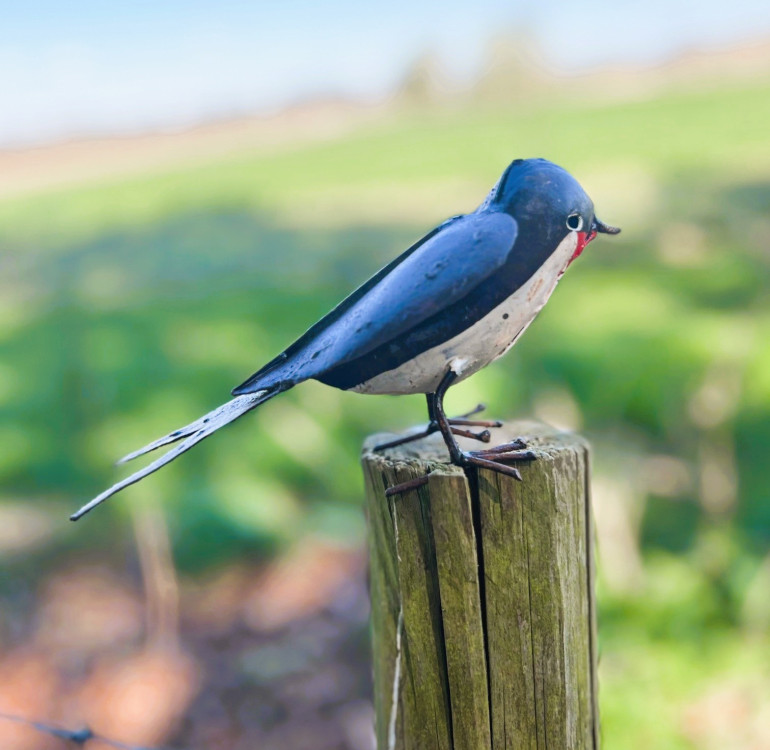 a handmade recycled metal little robin for outdoors with its wings open ready to fly