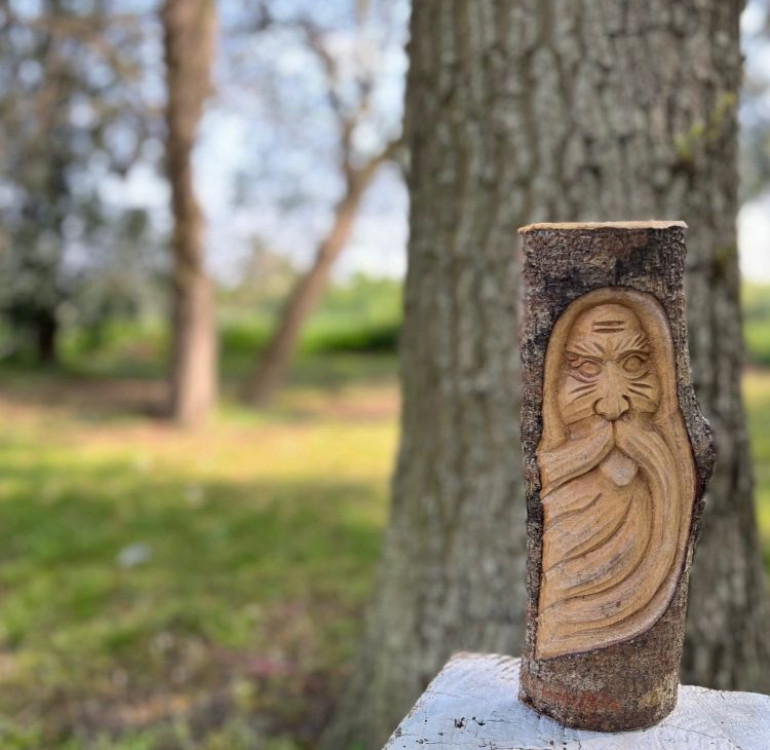 a hand carved wall hanging of a Green Man 30cm in length and made on a half log