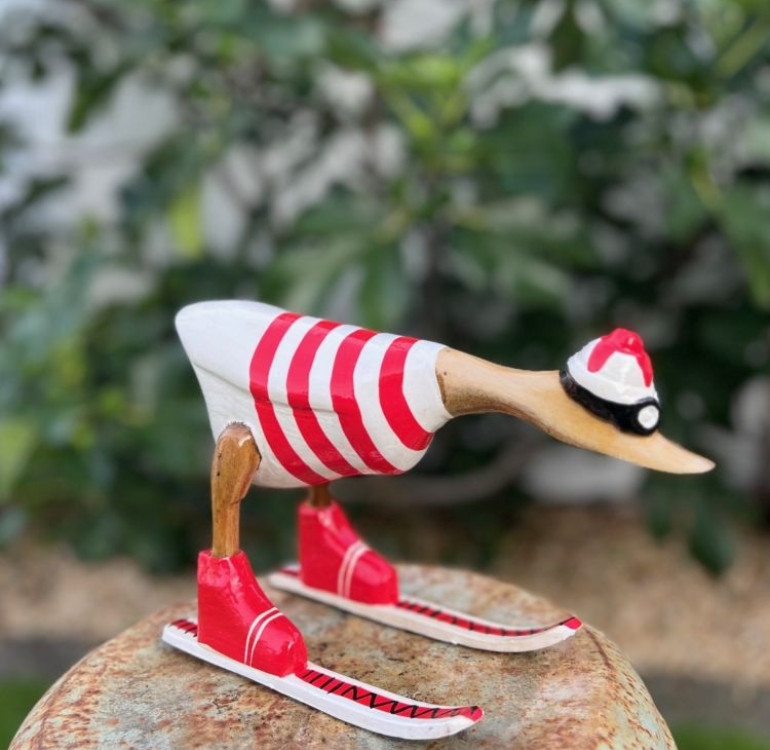 handmade bamboo duck dressed in a handpainted red and white striped outfit skiing