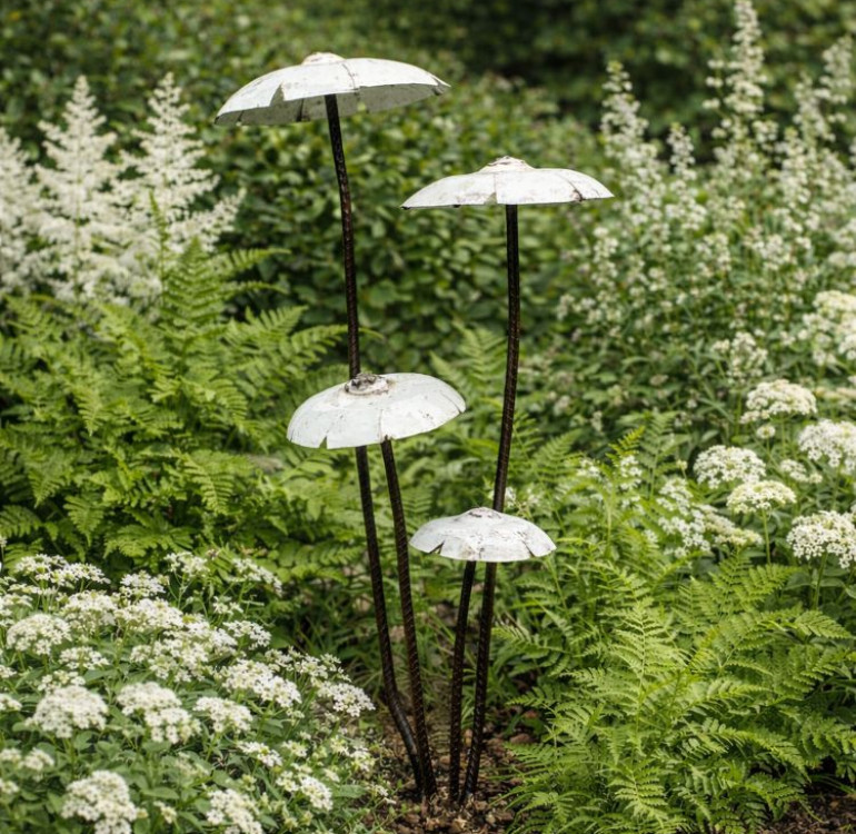 a garden sculpture of a set of white recycled metal mushrooms